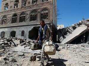 A Yemeni man carries his bags through the ruins of buildings destroyed in an air strike by the Saudi-led coalition in the capital Sanaa on October 28, 2015. (AFP/Mohammed Huwais)