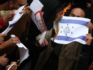 مناصرون للرئيس الفلسطيني عباس يحرقون علما يظهر نجمة شعار قناة الجزيرة مرسوما وسط نجمة داود في العلم الإسرائيلي!!