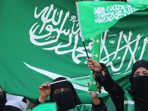 نساء سعوديات يحملن علم المملكة العربية السعودية