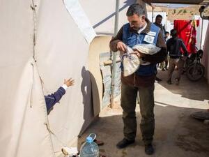 A volunteer from a Lebanese NGO distributes bread to Syrian refugees (AFP/File Photo)	