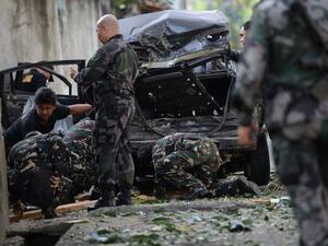 A members of Philippine police and military bomb squads look for evidence next to a destroyed car after a suspected car bomb explosion amidst heavy firefight between government troops and rebels. (AFP)
