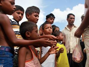 A Bangladeshi man distributes meat from a sacrificed animal to Rohingya refugees, during Eid al-Adha (AFP)