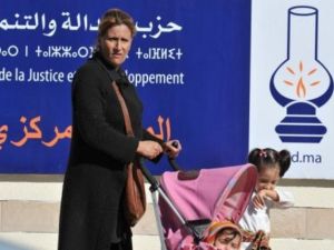 امراة تعبر مع اطفالها من امام لافتة انتخابية في الرباط