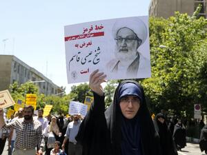 An Iranian protestor holds a banner bearing a portrait of top Bahraini Shiite cleric Isa Qassim, who was sentenced on May 21 to a suspended one-year jail term, during a demonstration in the capital Tehran on May 26, 2017 (STR/AFP)