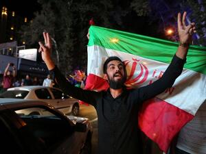 Iranian revelers brandish their national flag in celebration of a historic deal that would ease sanctions on the country and open its economy, July 14, 2015. (AFP/Atta Kenare)
