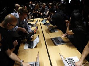 Members of the media gather around a table displaying the new Apple MacBook Pro laptop after the product launch event on October 27, 2016 in Cupertino, California. (AFP/Stephen Lam)