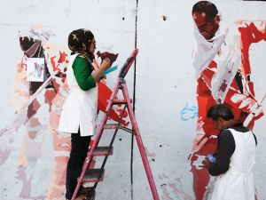 In this Thursday, Aug. 20, 2015 photo, independent Afghan artists paint on a barrier wall which blocks a main gate of the presidential palace in Kabul, Afghanistan. (File photo)