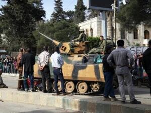 سوريون ينظرون الى دبابة تركية اثناء انتظارهم للحصول على مساعدات غذائية في عفرين 
