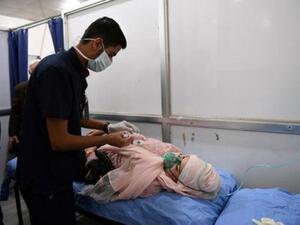 امرأة تحصل على مساعدة طبية في مستشفى في حلب بعد هجوم بالغاز يوم السبت
