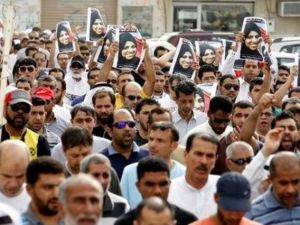 مشيعون يحملون صور المرلأة التي قتلت في حادث يوم الجمعة في المنامة عاصمة البحرين في جنازتها بقرية السترة يوم السبت
