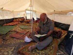 رجل فلسطيني يقرأ القرآن داخل خيمة خلال شهر رمضان في مخيم احتجاج قرب حدود إسرائيل مع قطاع غزة

