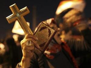 امرأة تحمل مصحفا وصليبا خلال مظاهرة في القاهرة
