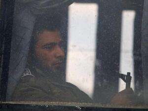 مقاتل في المعارضة السورية يمسك سلاحه على متن حافلة تستعد لمغادرة حي الوعر في حمص
