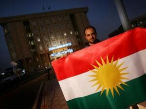 يحمل العلم الكردي امام مقر برلمان كردستان العراق في اربيل

