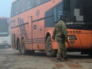 مقاتل من المعارضة يقف بجوار حافلة تقل سكانا من بلدتي الفوعة وكفريا بموجب اتفاق مع النظام في إدلب يوم الجمعة

