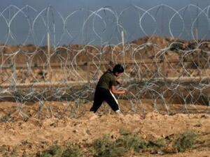 فتى فلسطيني يحاول قطع السياج الشائك عند الخط الفاصل بين قطاع غزة واسرائيل
