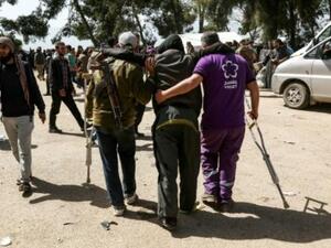 مقاتل من المعارضة السورية يحمل رشاشه فيما يساعد متطوع جريحا عند وصولهما الى قلعة المضيق بعد عملية الاجلاء من الغوطة الشرقية

