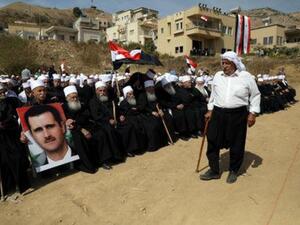 أشخاص من الدروز العرب ينظمون مسيرة ويرفعون صورة للرئيس السوري بشار الأسد قرب خط وقف إطلاق النار بين إسرائيل وسوريا في هضبة الجولان
