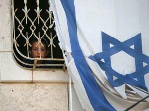 طفل ينظر عبر نافذة بيت فلسطيني يحتله مستوطنون في مدينة الخليل المحتلة والمقسمة.

