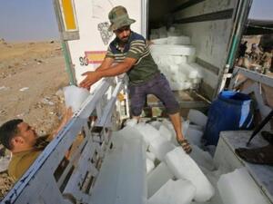 عراقيون يفرغون قوالب ثلج من شاحنة في تل عبطة جنوب تلعفر لتسليمها للمقاتلين العراقيين الذين يواجهون تنظيم الدولة الإسلامية على خطوط الجبهة في شمال العراق

