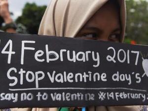 طالبة مسلمة في إندونيسيا تمسك بلافتة مكتوب عليها "أوقفوا عيد الحب" خلال مظاهرة ضد الاحتفال بعيد الحب في سورابايا بإندونيسيا
