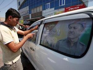 رجل كردي يضع ملصقا يحمل صورة رئيس كردستان العراق على سيارة في أربيل
