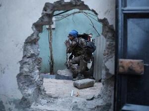 أحد جنود القوات الخاصة العراقية يمر عبر فتحة في جدار خلال عمليات بحث عن مقاتلين من تنظيم الدولة الإسلامية في الموصل

