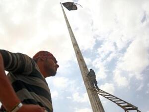 عنصر من قوات سوريا الديموقراطية ينزل راية لتنظيم الدولة الاسلامية في بلدة الطبقة
