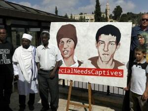 أقارب هشام السيد وأفيرا منغيستو أمام لافته تحمل صورتيهما في القدس
