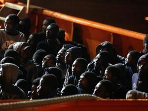 مهاجرون في انتظار نزولهم من على سفينة في ميناء أوجستا بصقلية في إيطاليا
