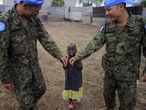 مهندسان من قوة الدفاع الذاتي اليابانية التابعة لقوات الامم المتحدة لحفظ السلام يداعبان طفلة في مركز للأطفال في جوبا بجنوب السودان
