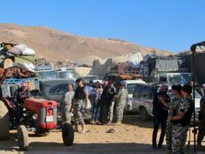 عناصر من الأمن اللبناني بالقرب من سيارات تقل لاجئين سوريين يستعدون لمغادرة لبنان
