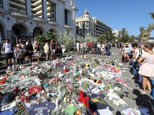 People gather near flowers placed at a makeshift memorial near the Promenade des Anglais in Nice on July 17, 2016, in tribute to the victims of the Bastille Day attack that left 84 dead. (AFP/Valery Hache