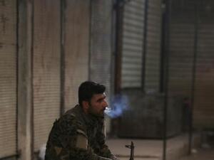 مقاتل من قوات سوريا الديمقراطية يدخن سيجارة في مدينة منبج بحلب
