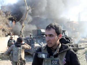 أحد أفراد القوات الخاصة العراقية يمشي أمام سيارة همفي بعد تفجير انتحاري نفذه أحد مقاتلي تنظيم الدولة الإسلامية في الموصل
