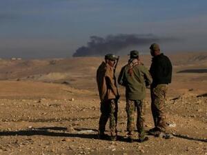 دخان متصاعد وراء أفراد من قوات التدخل السريع العراقية جراء معارك مع تنظيم الدولة الإسلامية إلى الجنوب من الموصل يوم الاثنين
