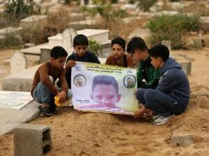 اصدقاء الفتى الفلسطيني محمد ايوب الذي قتل برصاص القوات الاسرائيلية على الحدود بين غزة واسرائيل يحملون صورته فوق قبره في بيت لاهيا في شمال قطاع غزة
