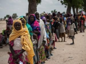 نساء واطفال ينتظرون في طابور امام عيادة ليونيسيف في مخيم عشوائي يأوي
