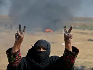 امرأة فلسطينية ترفع شارة النصر خلال احتجاجات على حدود قطاع غزة مع اسرائيل
