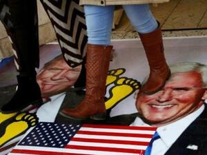 فلسطينيون يدوسون على ملصق عليه صورتي ترامب وبنس، خلال تظاهرة في جامعة القدس المفتوحة في قرية دورا قرب الخليل
