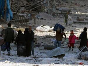 أشخاص يسيرون وسط حطام مبان مدمرة في شرق حلب
