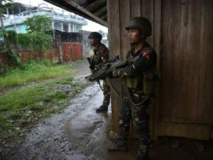 قوات فيليبينية تتمركز في مواجهة قناصة في أثناء مواكبتها عمالا وسكانا علقوا وسط الاشتباكات بين الجيش ومقاتلين جهاديين في مدينة مراوي في جزيرة منداناو
