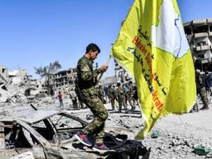 مقاتل من قوات سوريا الديمقراطية يغرس علم القوات الأصفر في ساحة في الرقة كان تنظيم الدولة الاسلامية يستخدمها في تنفيذ عمليات اعدام وصلب وتعليق جثث اثناء سيطرته على المدينة.

