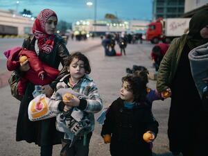 Migrant mothers with her children received oranges upon their arrival to the port of Piraeus in Athens area along with other migrants from the Greek Islands of Lesbos and Chios on February 18, 2016. (AFP/Louisa Gouliamaki)
