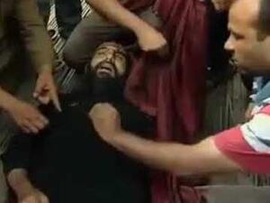 اشخاص يتجمهرون حول جثة القس سمعان بعيد مقتله

