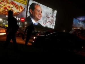 أشخاص يسيرون بالقرب من لوحة إعلانية تظهر صورة الرئيس المصري عبد الفتاح السيسي خلال الانتخابات الرئاسية في القاهرة
