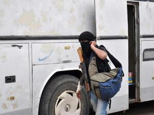 مسلح سوري معارض يستعد لركوب حافلة لمغادرة حي الوعر في حمص
