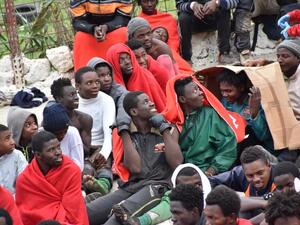 Migrants sit on the ground in El Tarajal, Ceuta, close to the border with Morocco on December 9, 2016 after being rounded up by police to be attended to by Red Cross personnel and taken to the Center for Temporary Stay of Immigrants. (AFP/ Antonio Sempere)