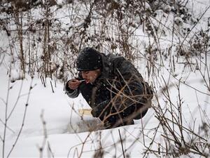 A refugee eats his meal while sitting in the snow in Belgrade on January 11, 2017, as temperatures drop to -15 degrees Celsius. (AFP/File) 