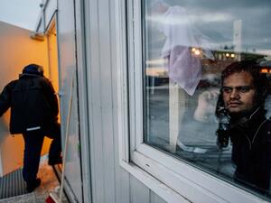 A refugee looks through a window at the arrival centre for refugees near the town on Kirkenes in northern Norway on Nov. 11, 2015. (AFP/Jonathan Nackstrand)